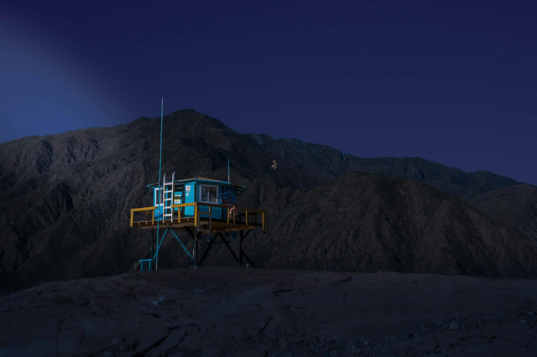 Oświetlone nocą górskie schronisko na tle wysokich szczytów