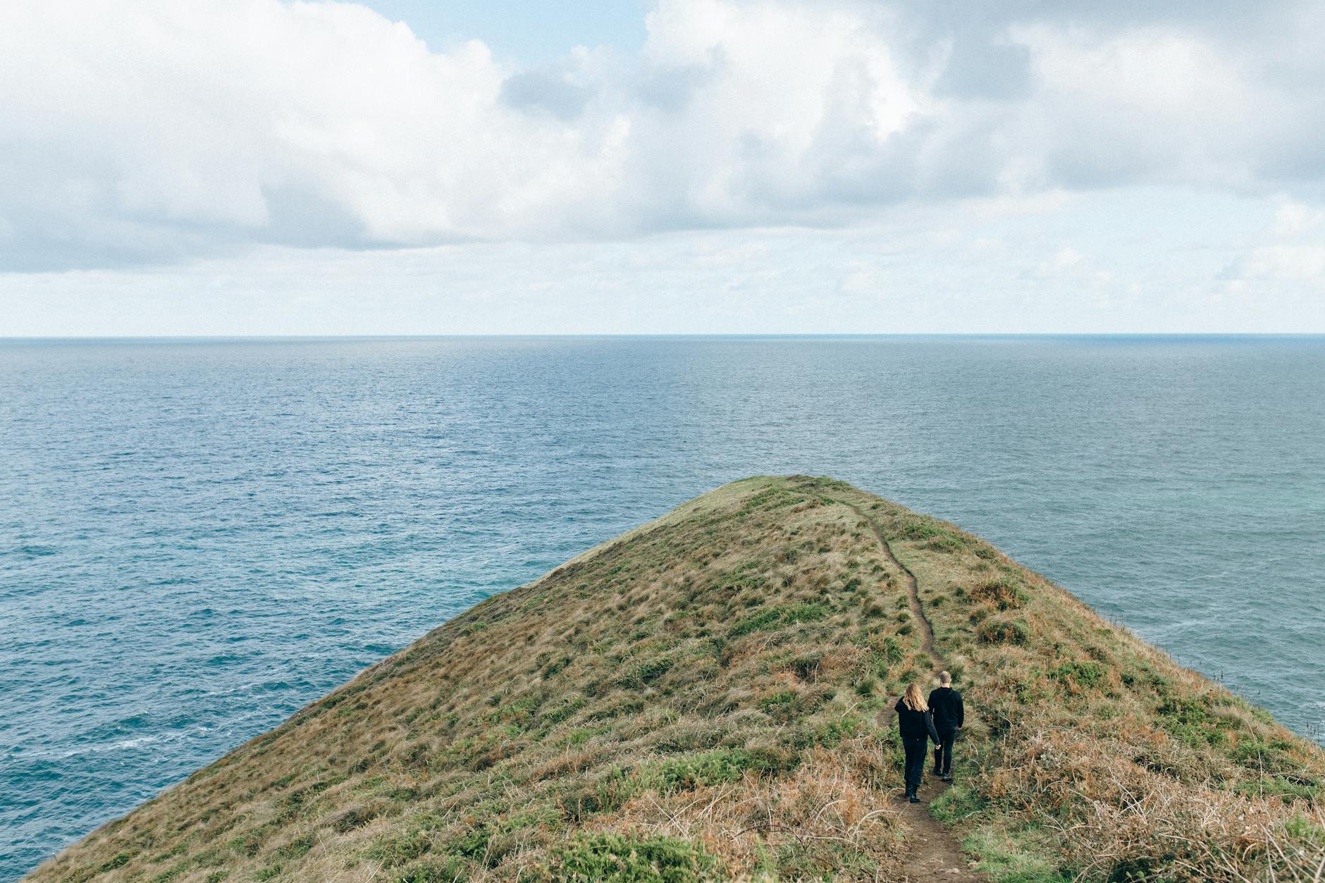 Para na szlaku pośród trawiastych klifów z widokiem na ocean