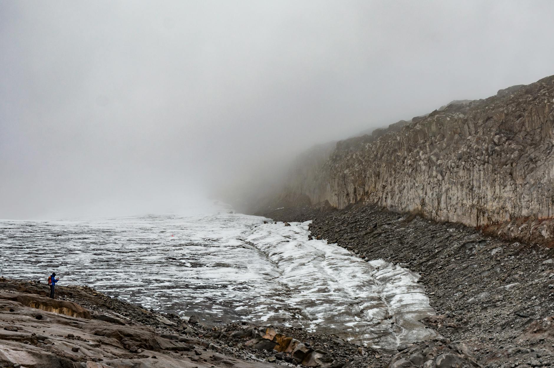Samotny turysta na tle mglistych gór w surowym, lodowcowym krajobrazie
