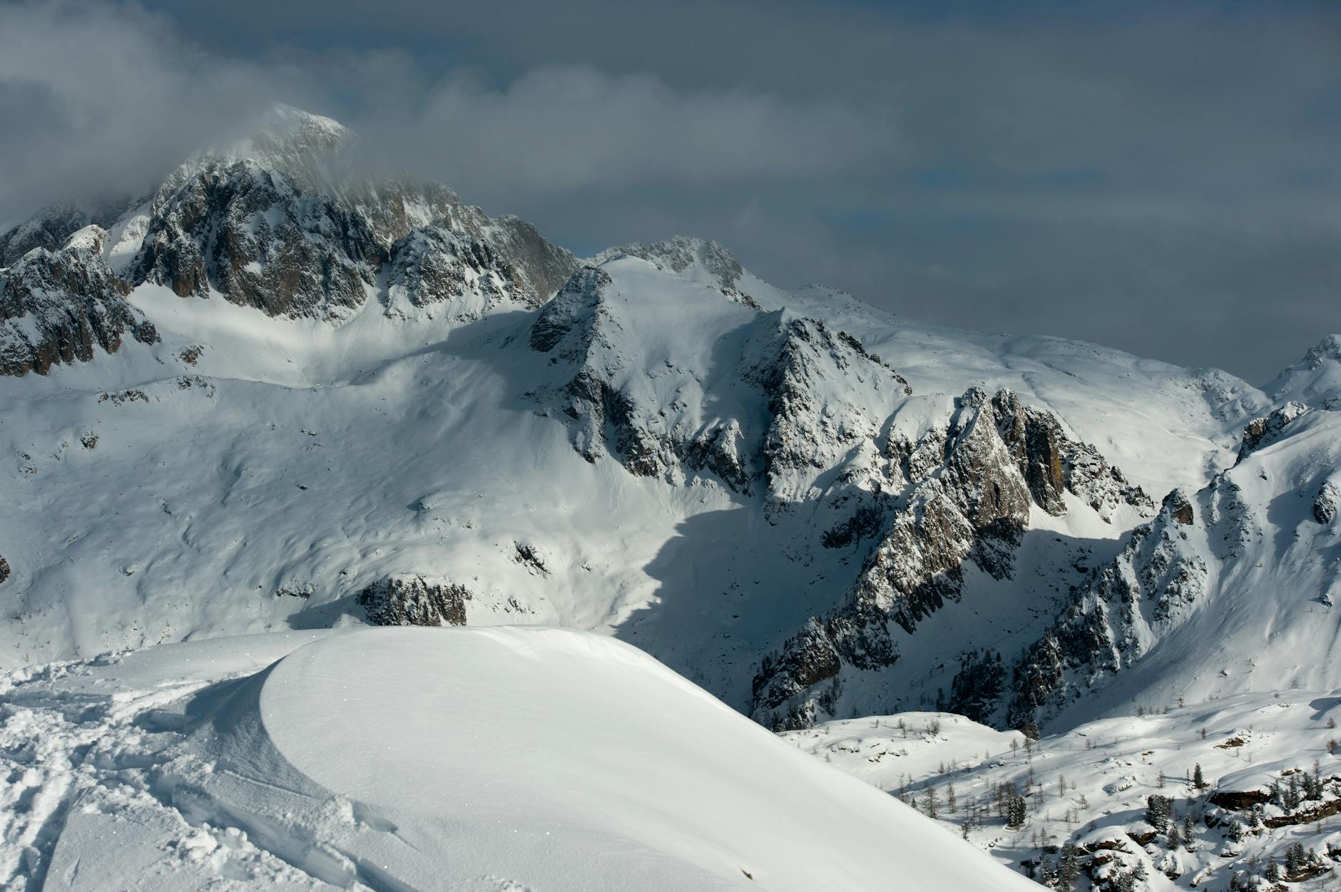 Ośnieżone szczyty górskie pod zachmurzonym, zimowym niebem