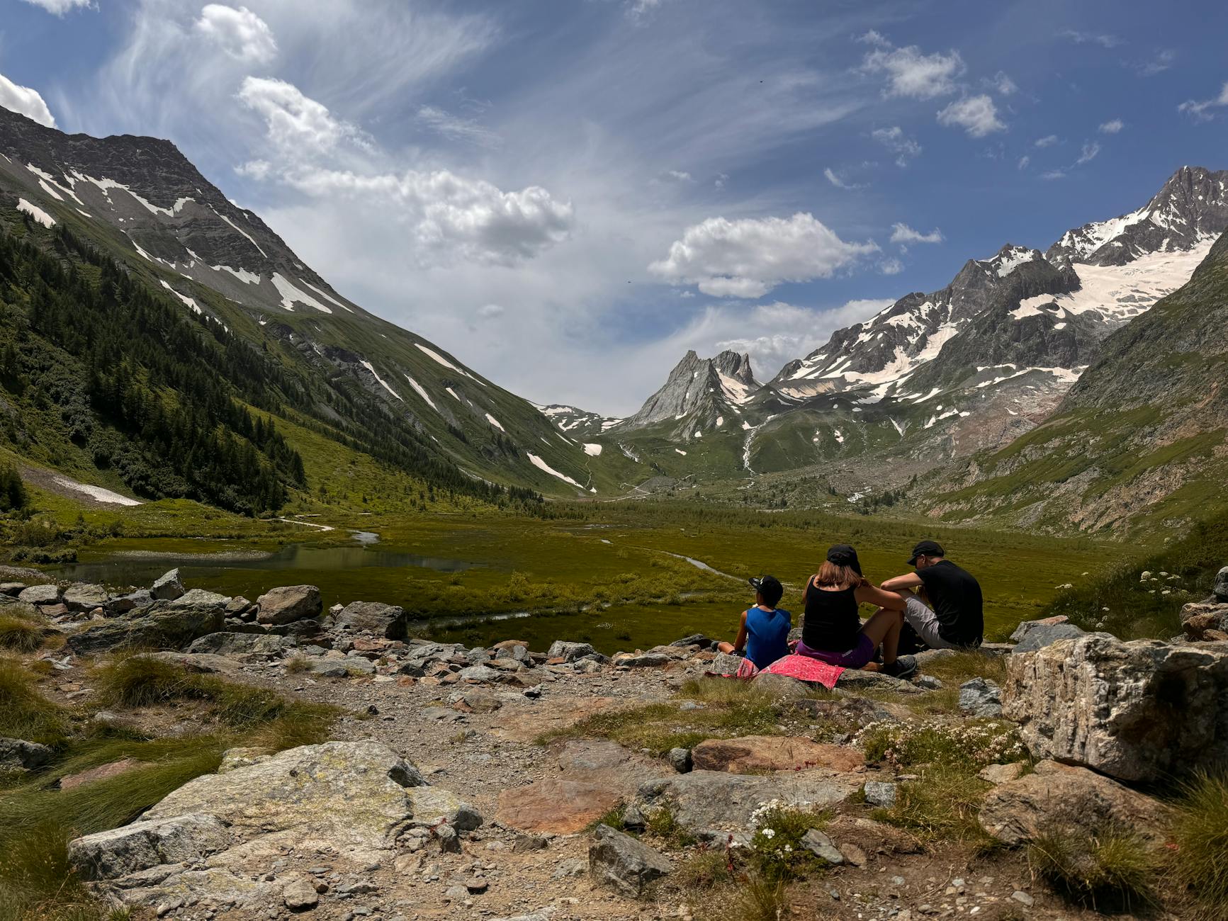 Rodzina na letnim szlaku w Tatrach z ośnieżonymi szczytami w tle