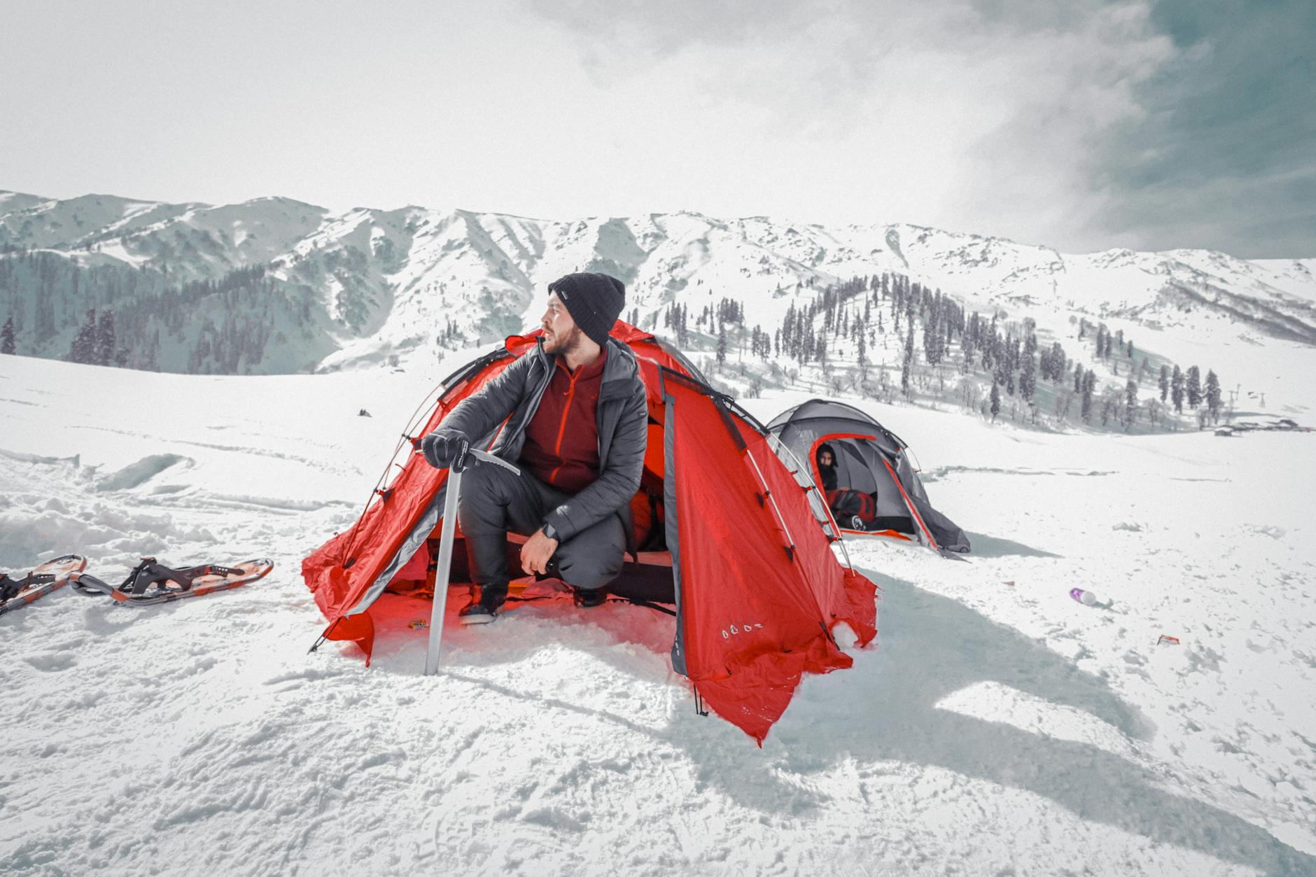 Turysta przy czerwonym namiocie w ośnieżonych Tatrach zimą